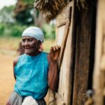 old lady leaning on a wooden house