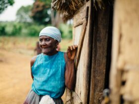 old lady leaning on a wooden house