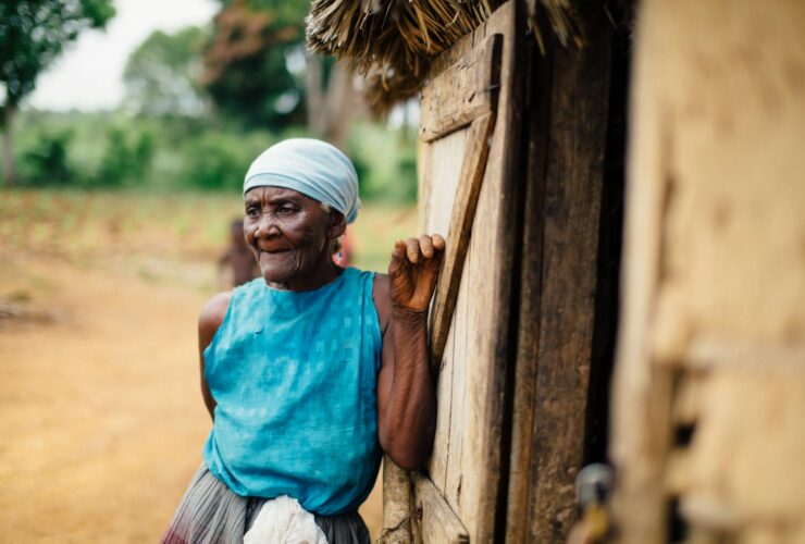 old lady leaning on a wooden house