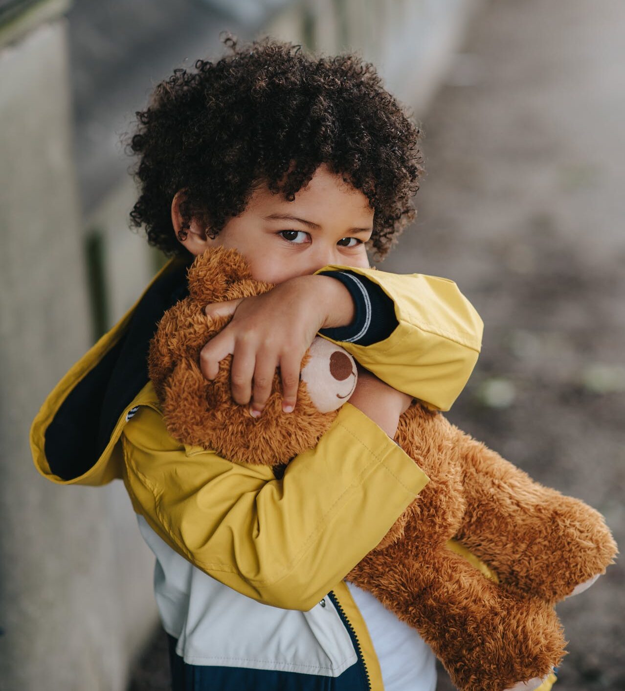 childing hugging a teddy bear and hiding mouth